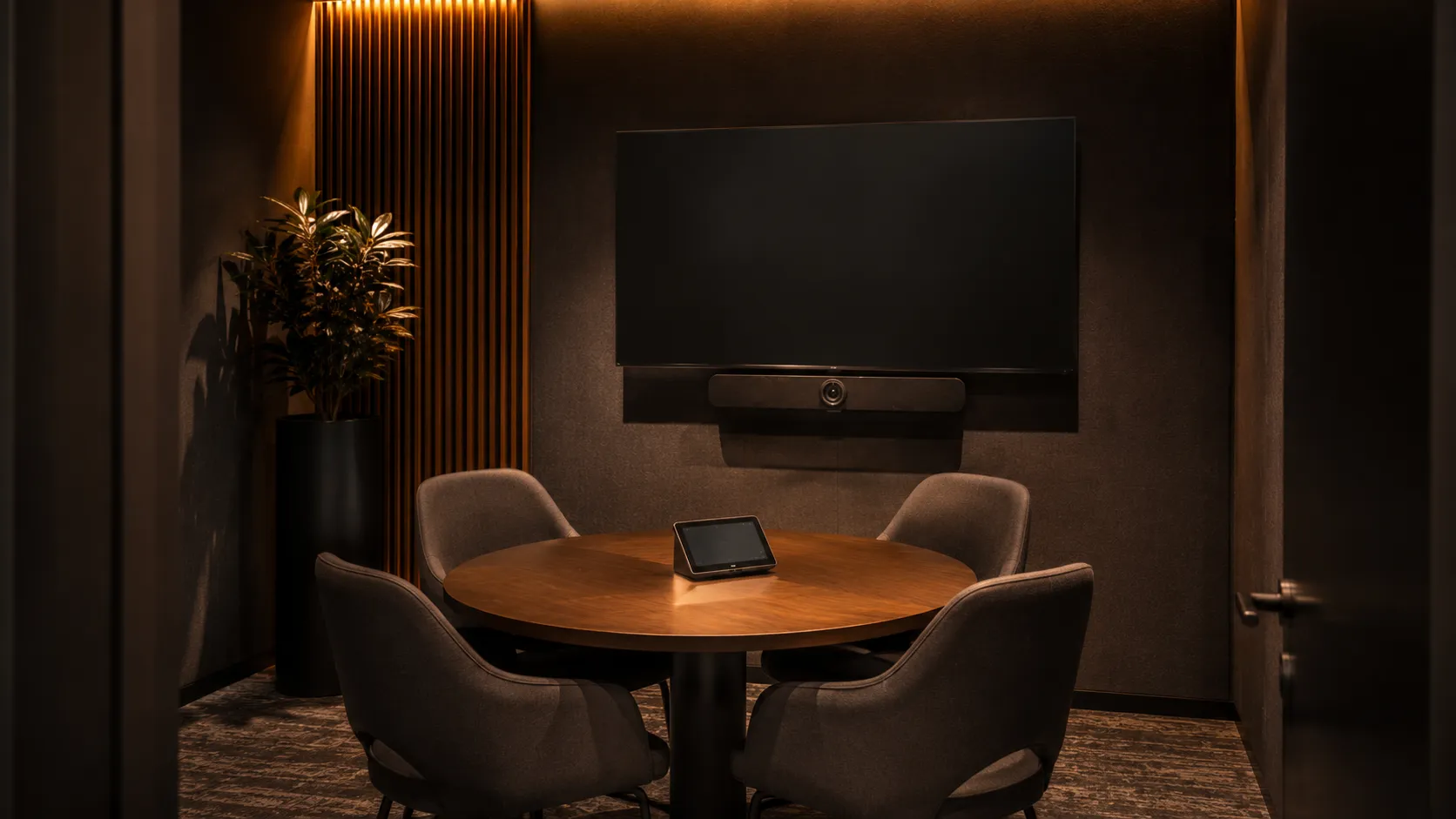 Medium Meeting Room & Conference Room Video Conferencing Australia 8 Small meeting room or huddle space with 2 to 4 person table, all-in-one video conferencing bar mounted below display, warm amber lighting — Kickstart Computers Australia